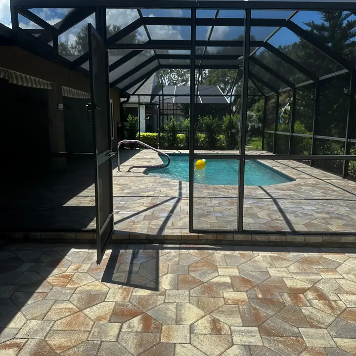 Clean restored pool deck pavers surrounding a screened swimming pool